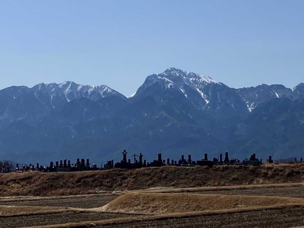 山を背に、墓地と田んぼが広がる風景