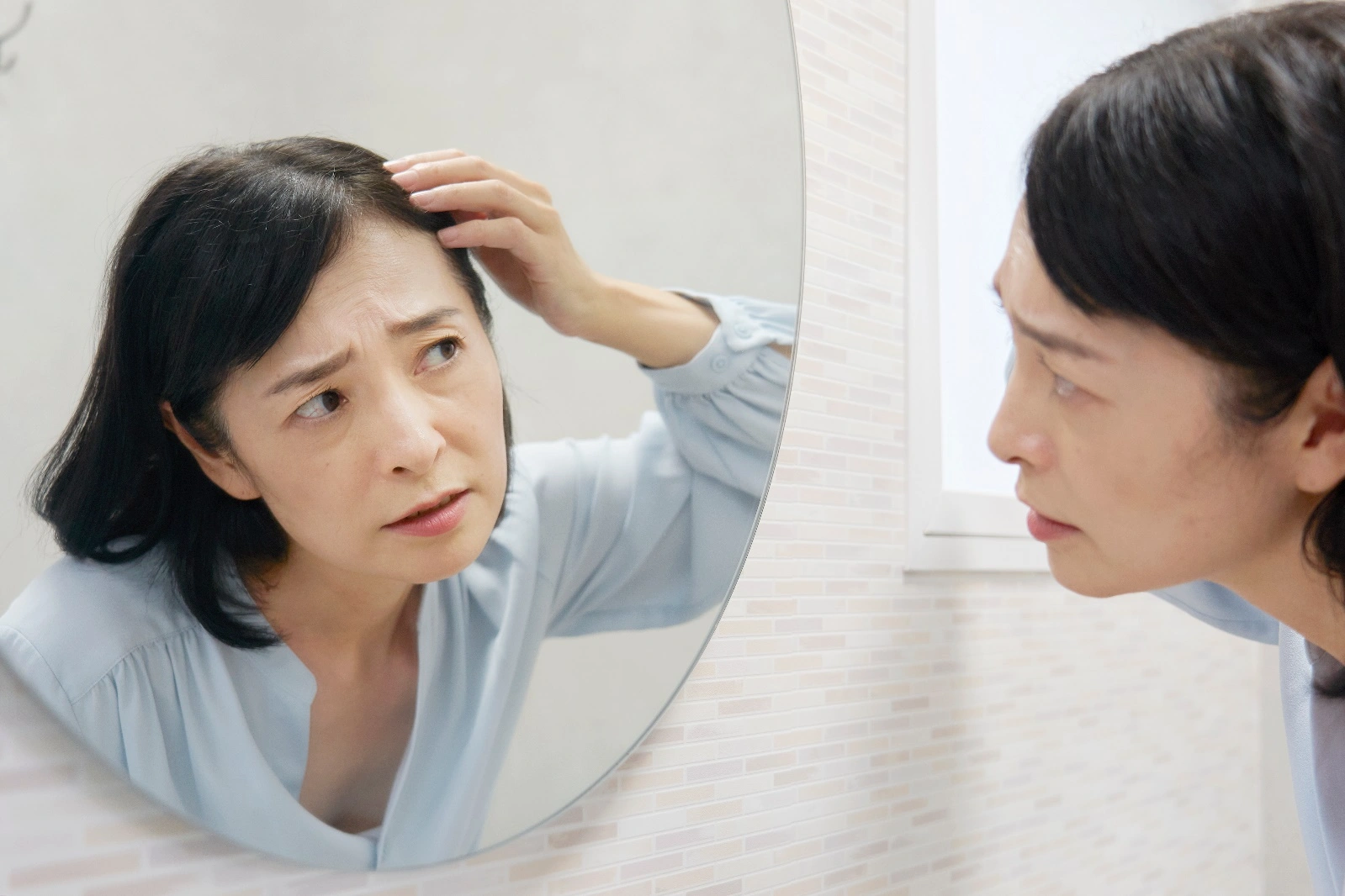 鏡を見て悩む女性